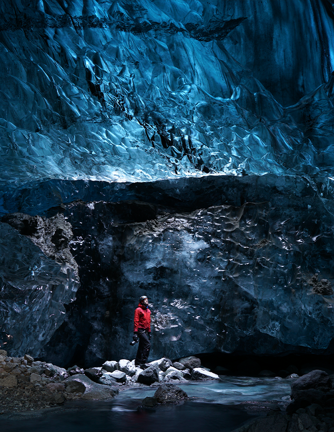 Женщина в длинном синем платье стоит на сцене перед пустым театром.
